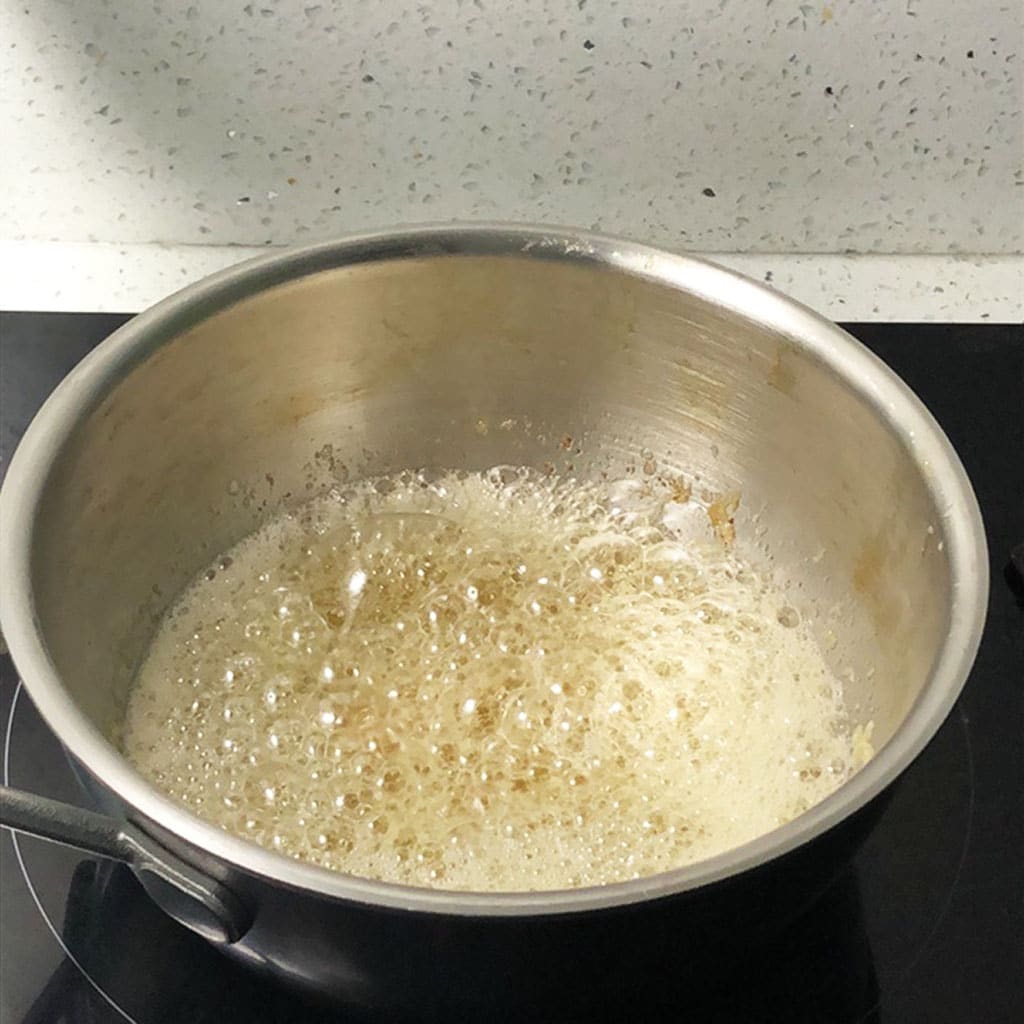 Boiling butter is foaming in a saucepan.