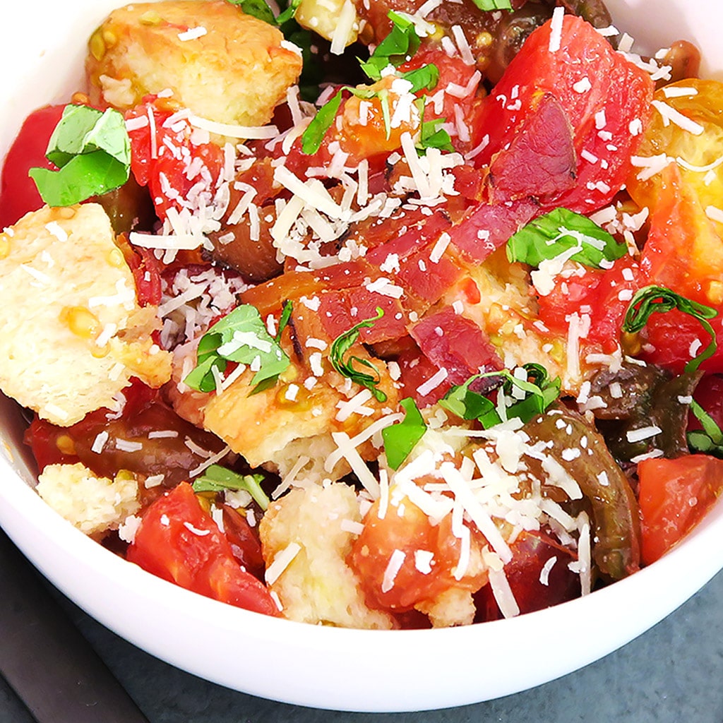 Topdown view of Tomato and Bread Salad, with fresh basil, and garlic. Bacon and cheese shown are optional ingredients.