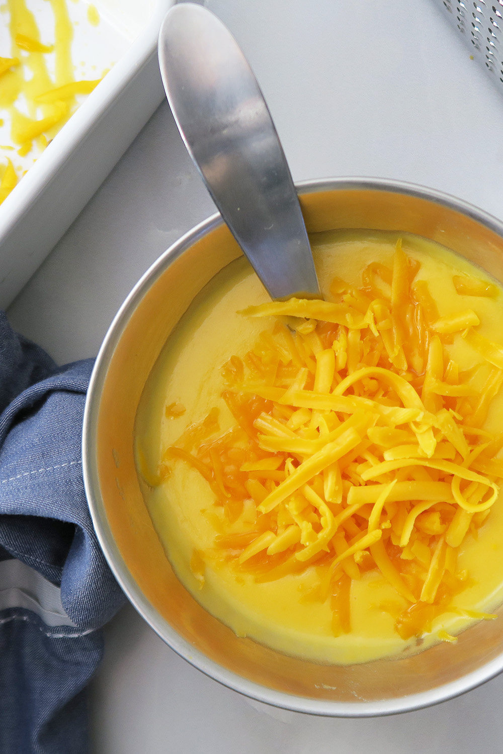 Top-down view of cheddar cheese sauce with grated cheddar on top