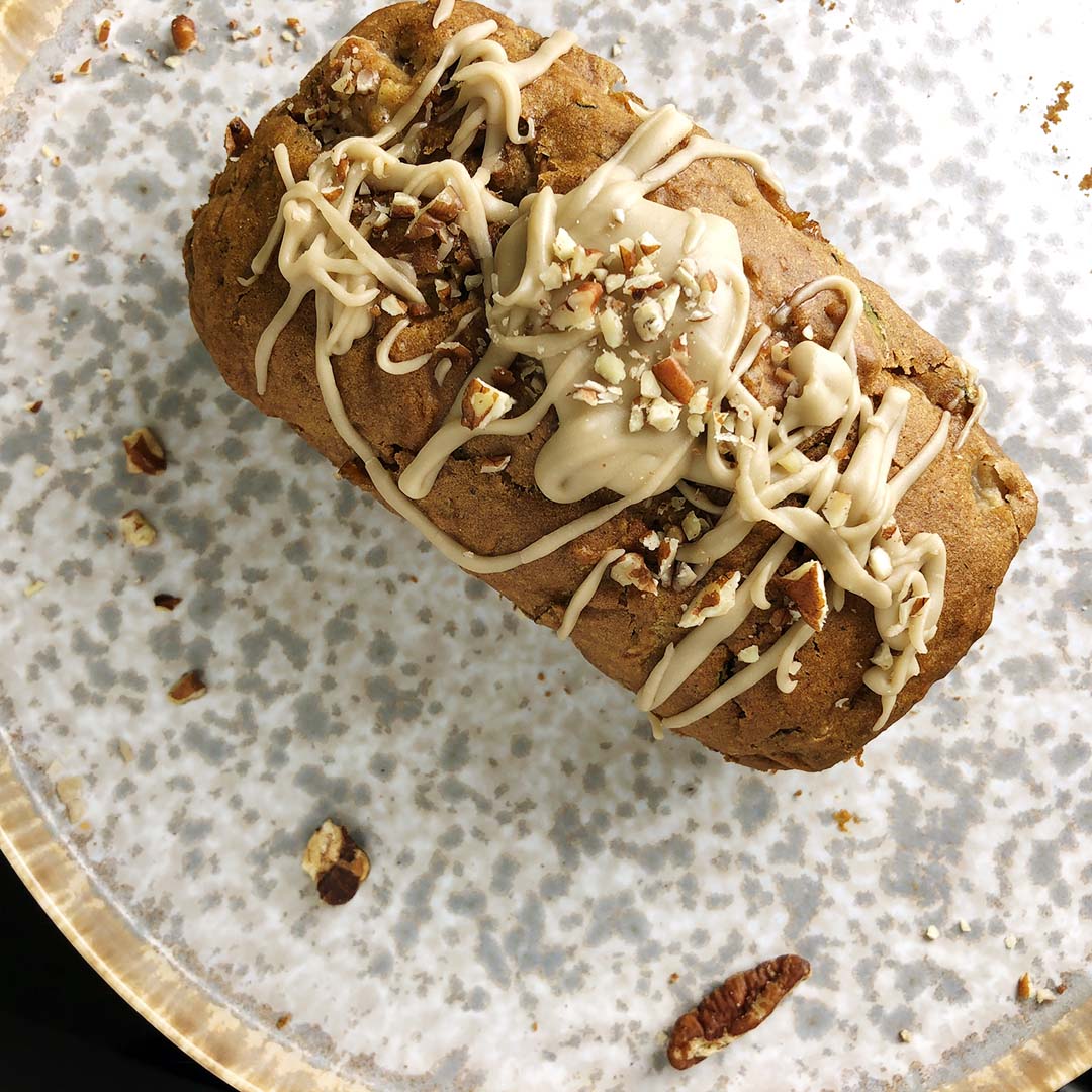 Top down shot of pear zucchini loaf drizzled with vanilla pecan glaze