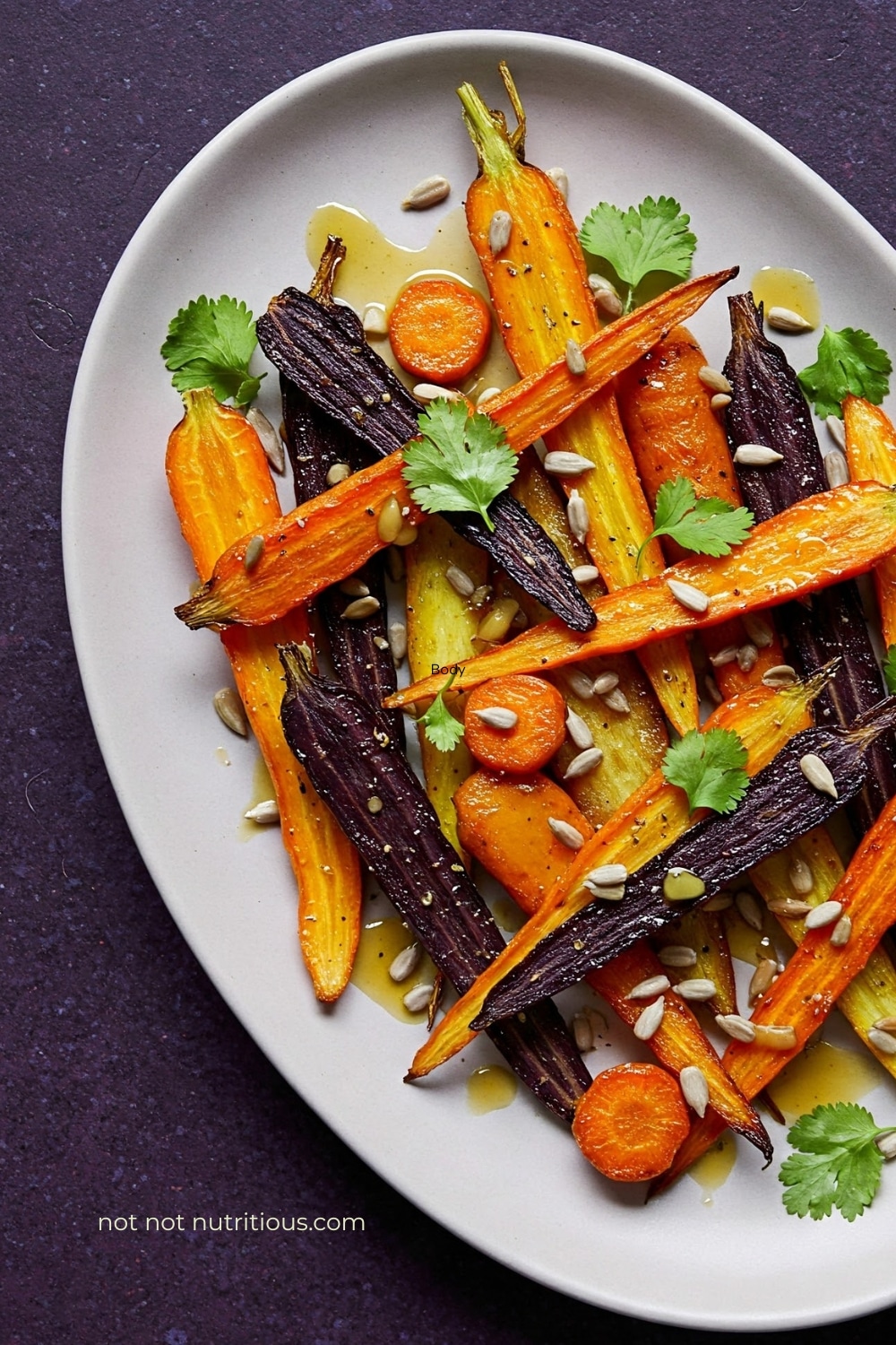 Top-down view of colorful rainbow carrots topped with cilantro, sunflower seeds and ginger brown butter