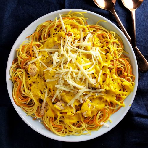 Plateful of multi-coloured spaghetti topped with Kabocha Squash and Cheddar Cheese Pasta Sauce with chicken.