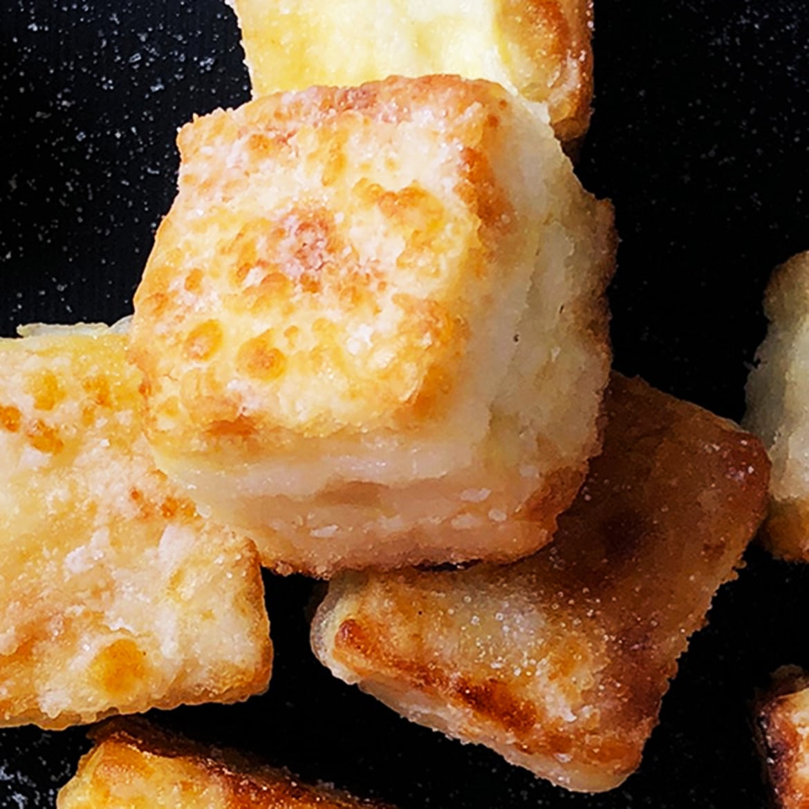 Close-up, top-down shot of cubes of salty crispy tofu