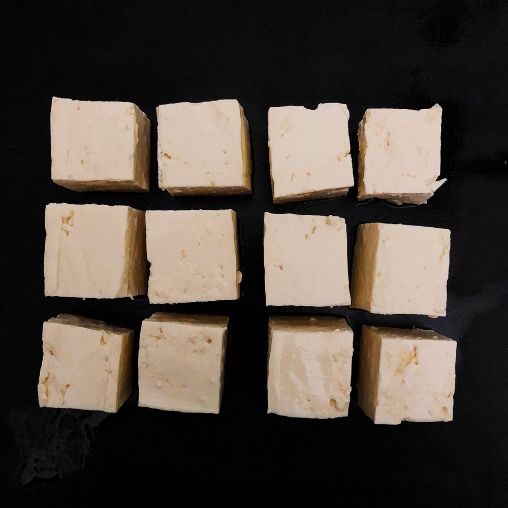 Top-down view of medium tofu cut into about one inch cubes. 