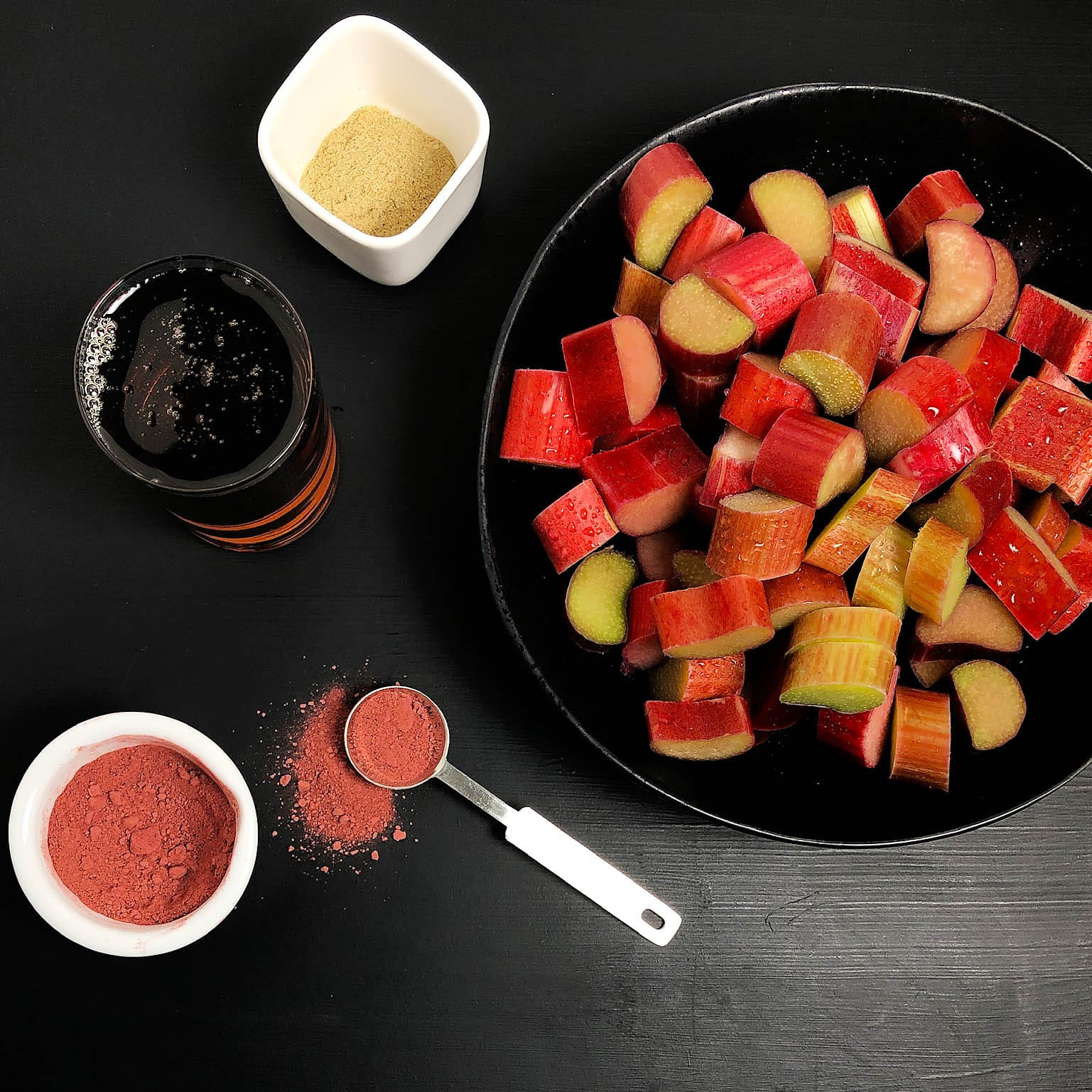 Top-down view of the ingredients for maple rhubarb compote: rhubarb, optional beet root powder, maple syrup, and cardamom
