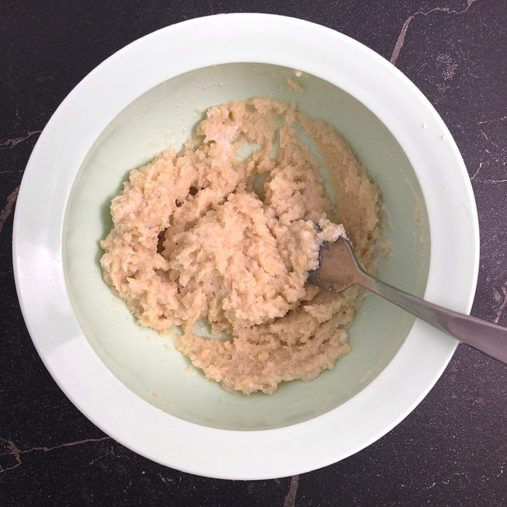 Top down view of vegan ricotta cheese in mixing bowl with fork