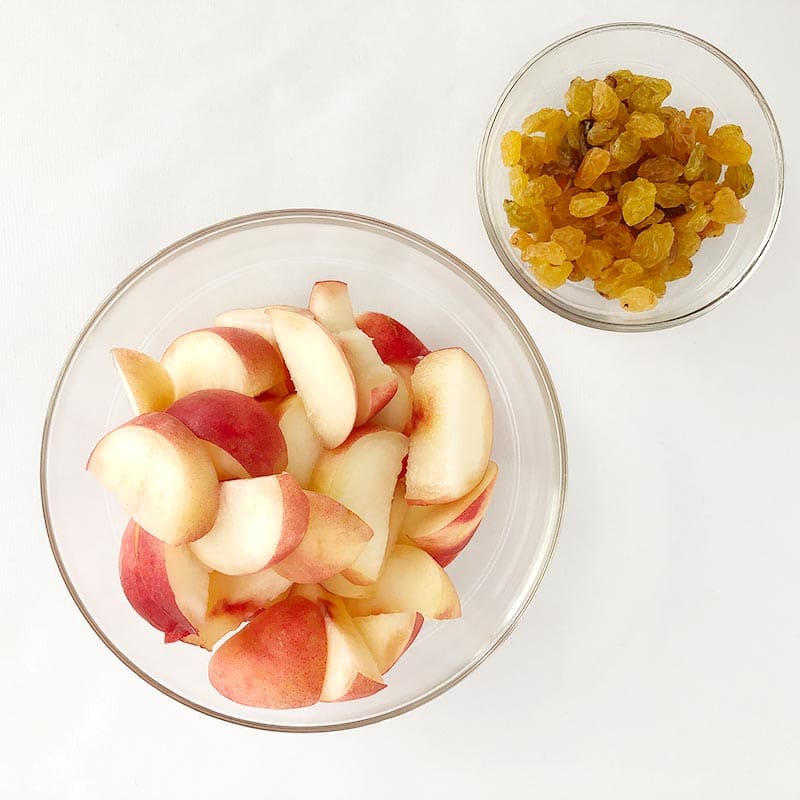 Top-down shot of raisins in a bowl and donut peaches in another bowl