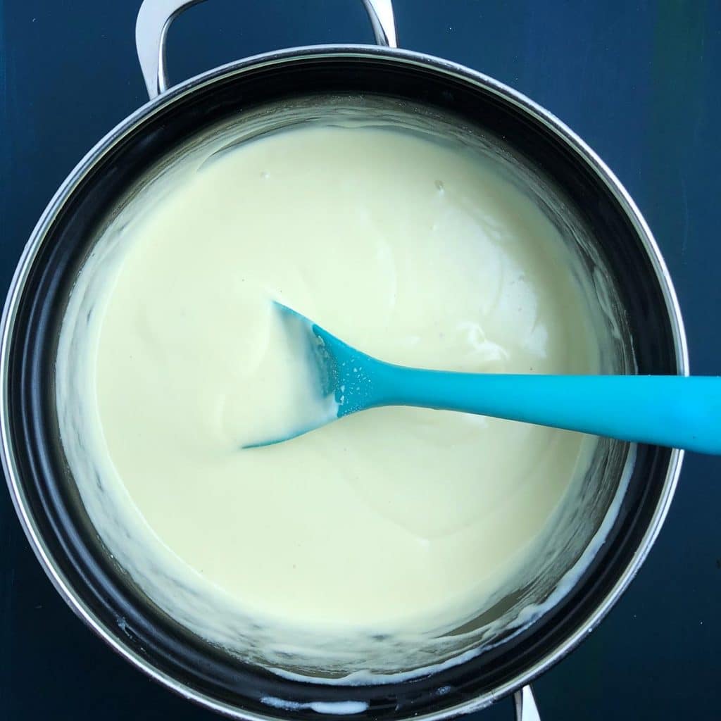 Top-down view of Mother Mix sauce base, cooked in saucepan with a blue spatula