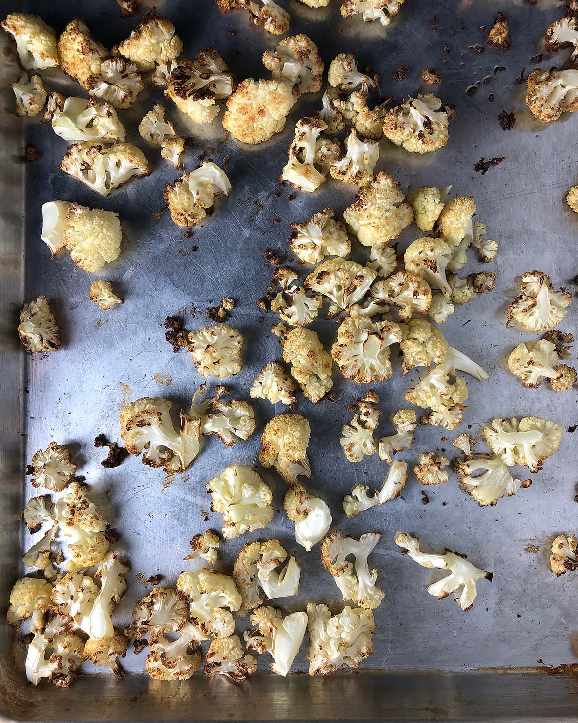 Topdown view of roasted cauliflower. Cauliflower is golden brown and the edges are dark brown and crispy.
