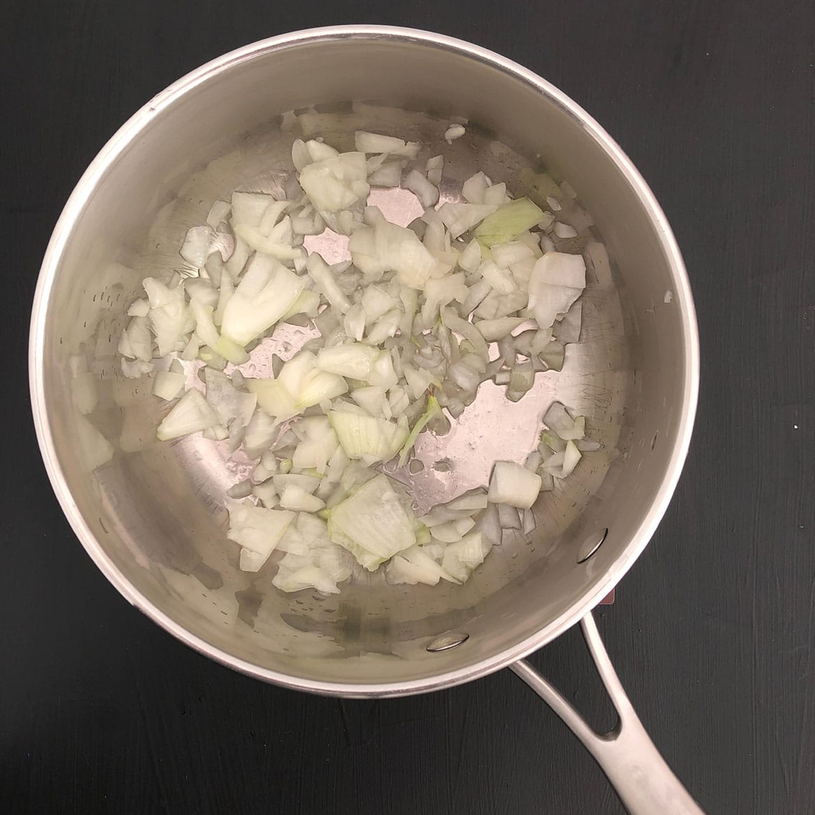 Top-down view of onions in a saucepan.
