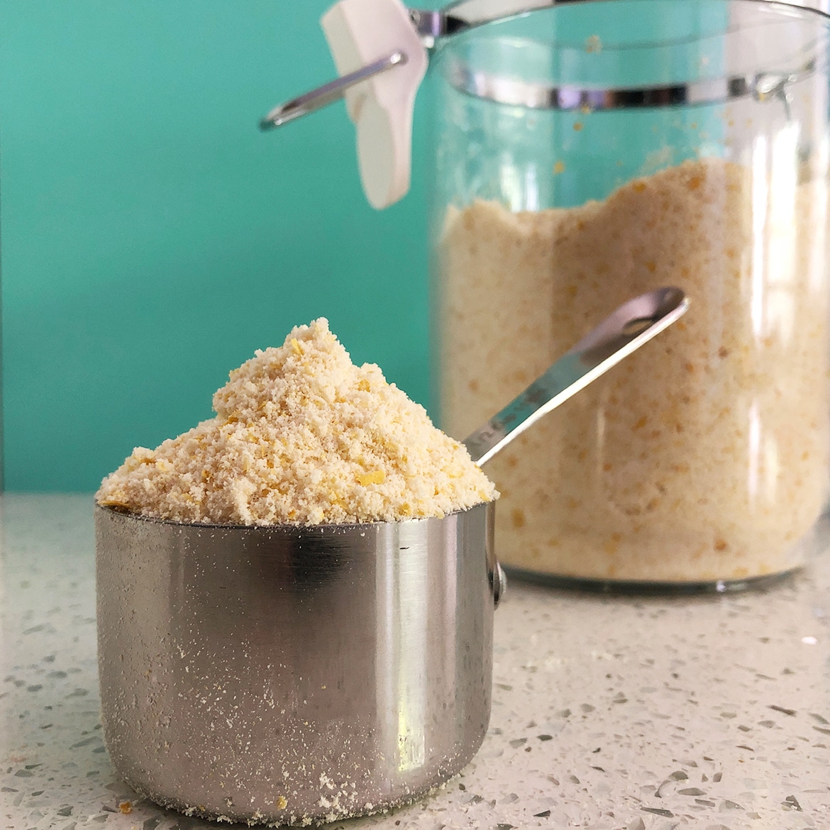 Measuring cup heaped full with the Mother Mix, made from almond flour, nutritional yeast, tapioca starch, and salt