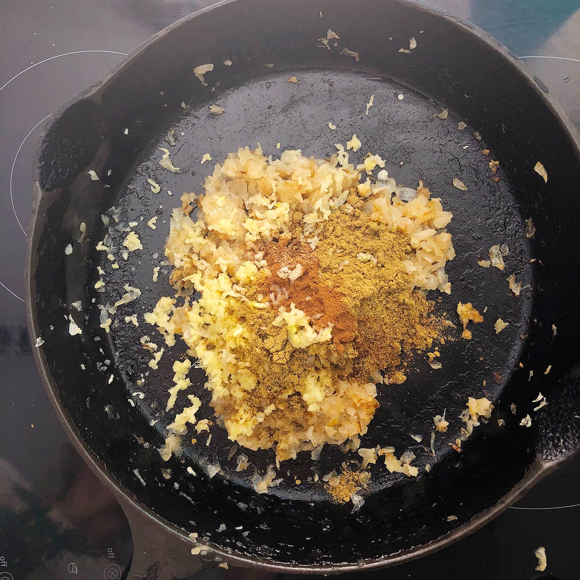 Top-down view of spices added to fried onions. Making Indian-Inspired Cashew Sauce.