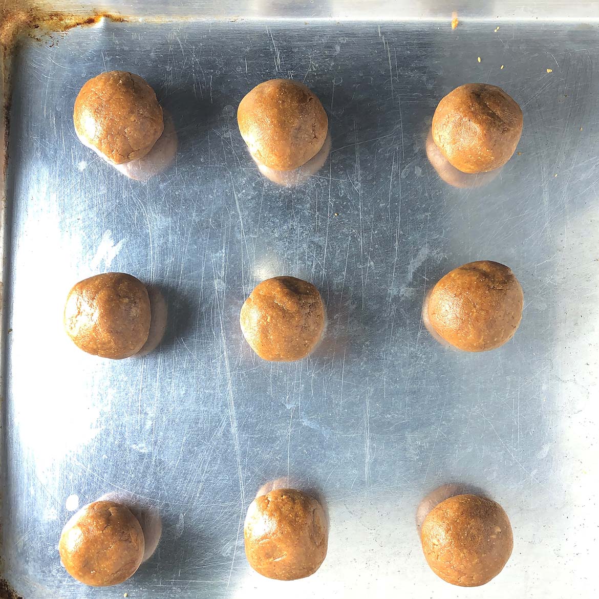 Top-down view of balls of Peanut Butter Cookie dough on baking sheet.