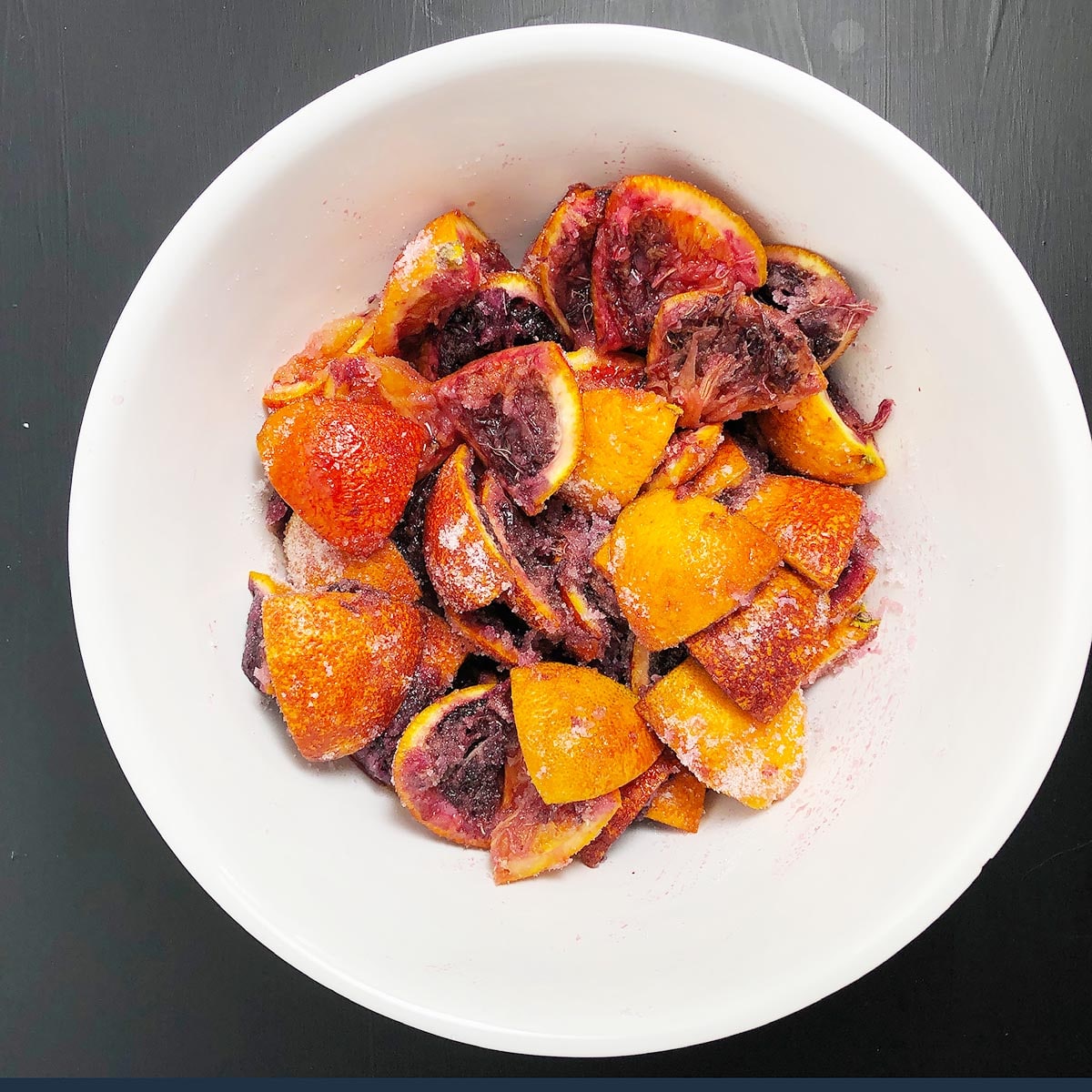 Blood orange peels in a large bowl, topped with white sugar