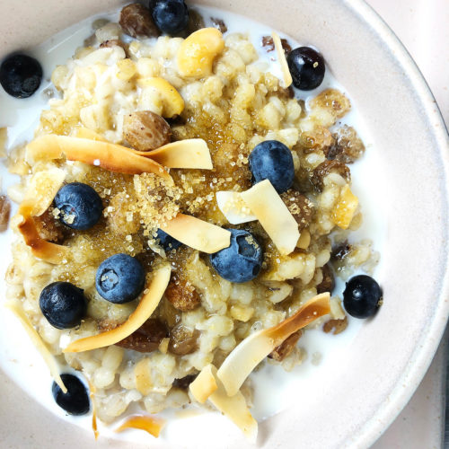 Top-down view of 1-Pot Barley Porridge topped with toasted coconut and blueberries.