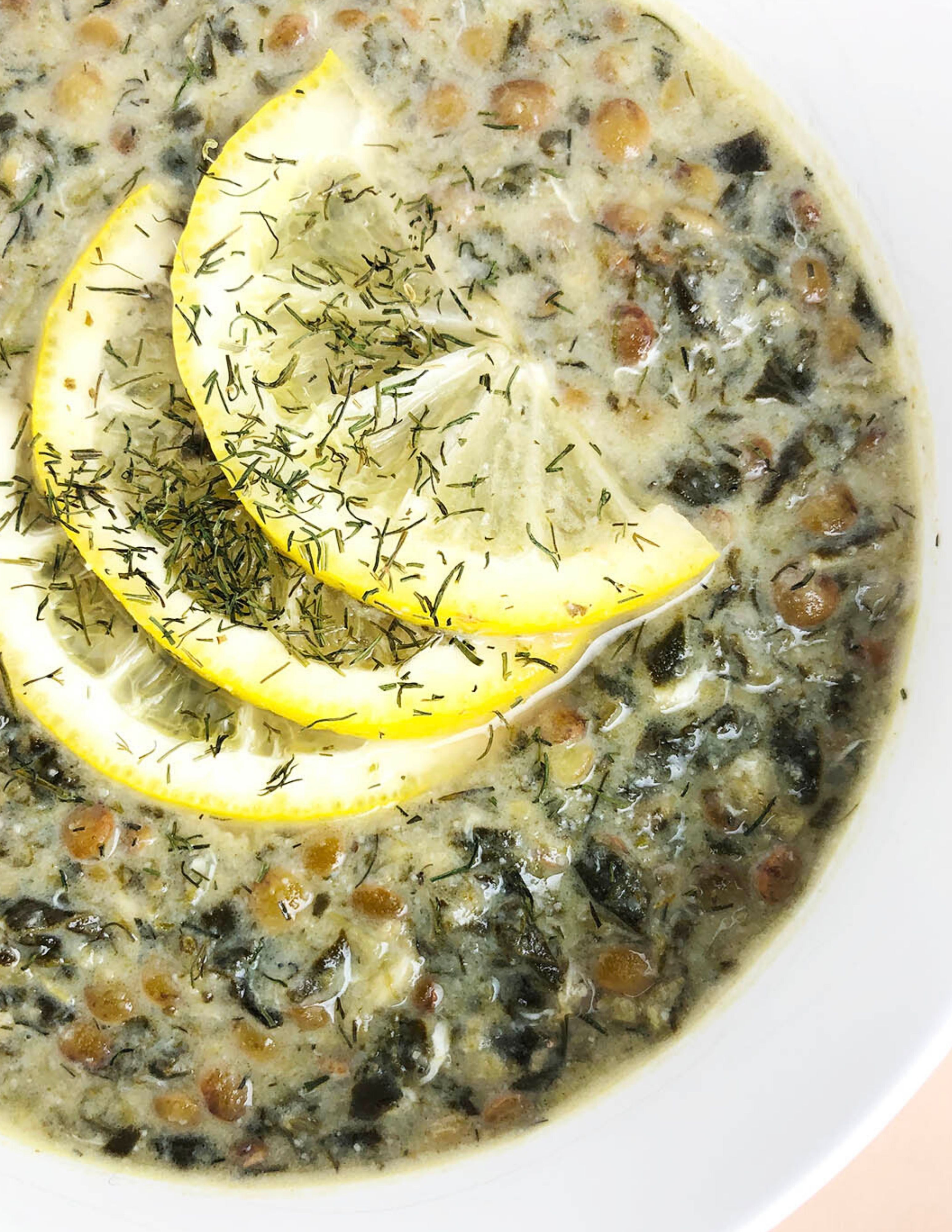 Top-down shot of Lentil, Lemon, and Dill Soup, garnished with lemon slices and dried dill.