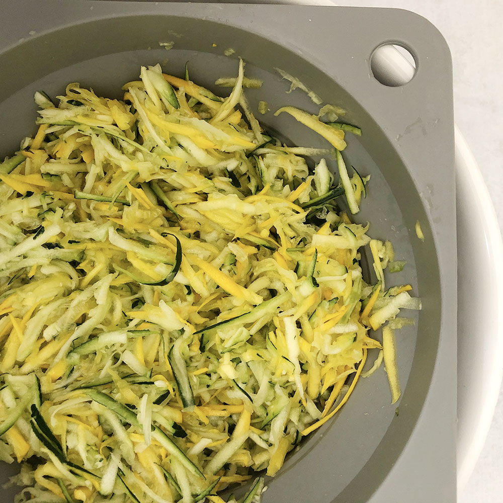 Top-down view of shredded zucchini in a colander