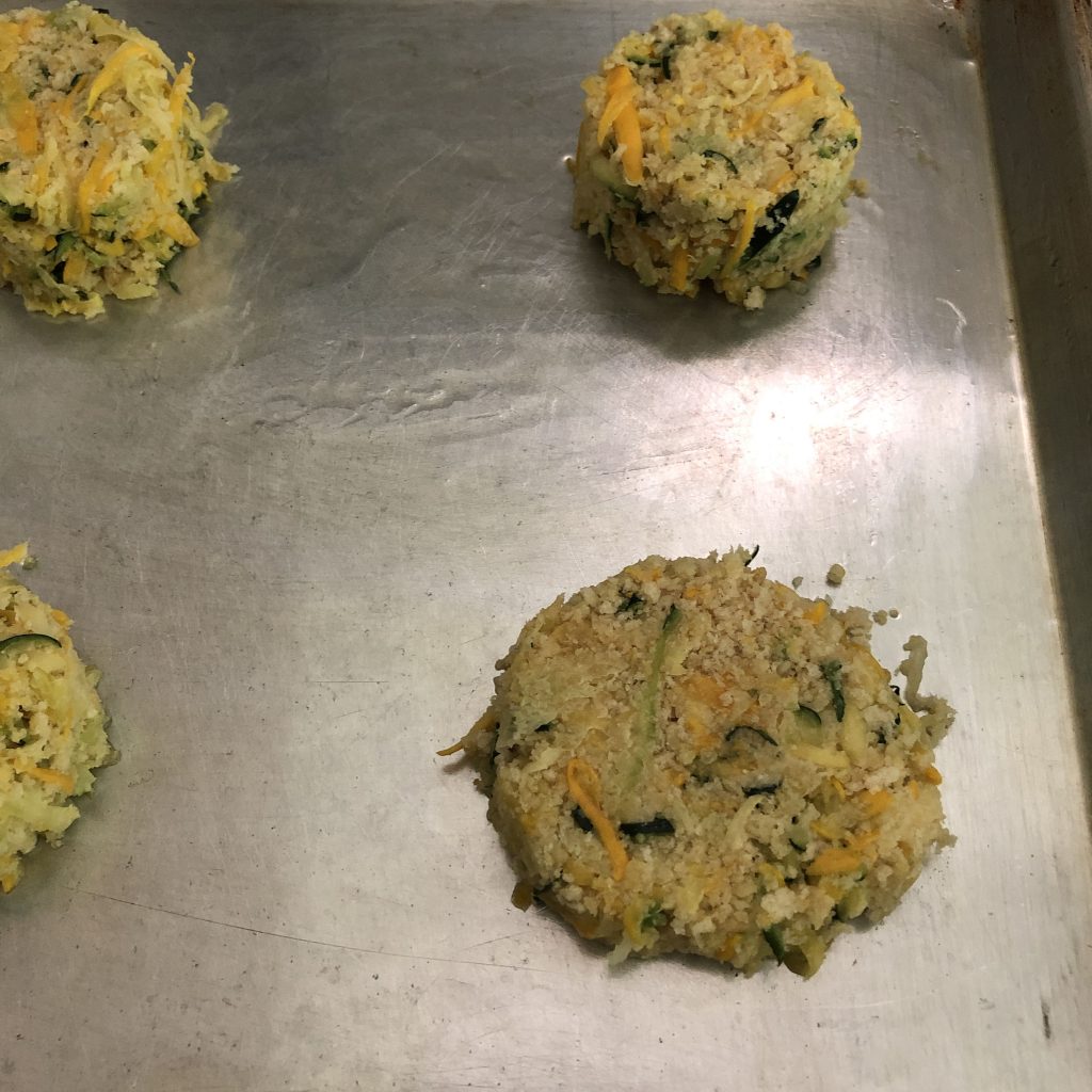 Making zucchini fritters - Tap the filled measuring cup upside down on the baking sheet. Press the fritter batter down.