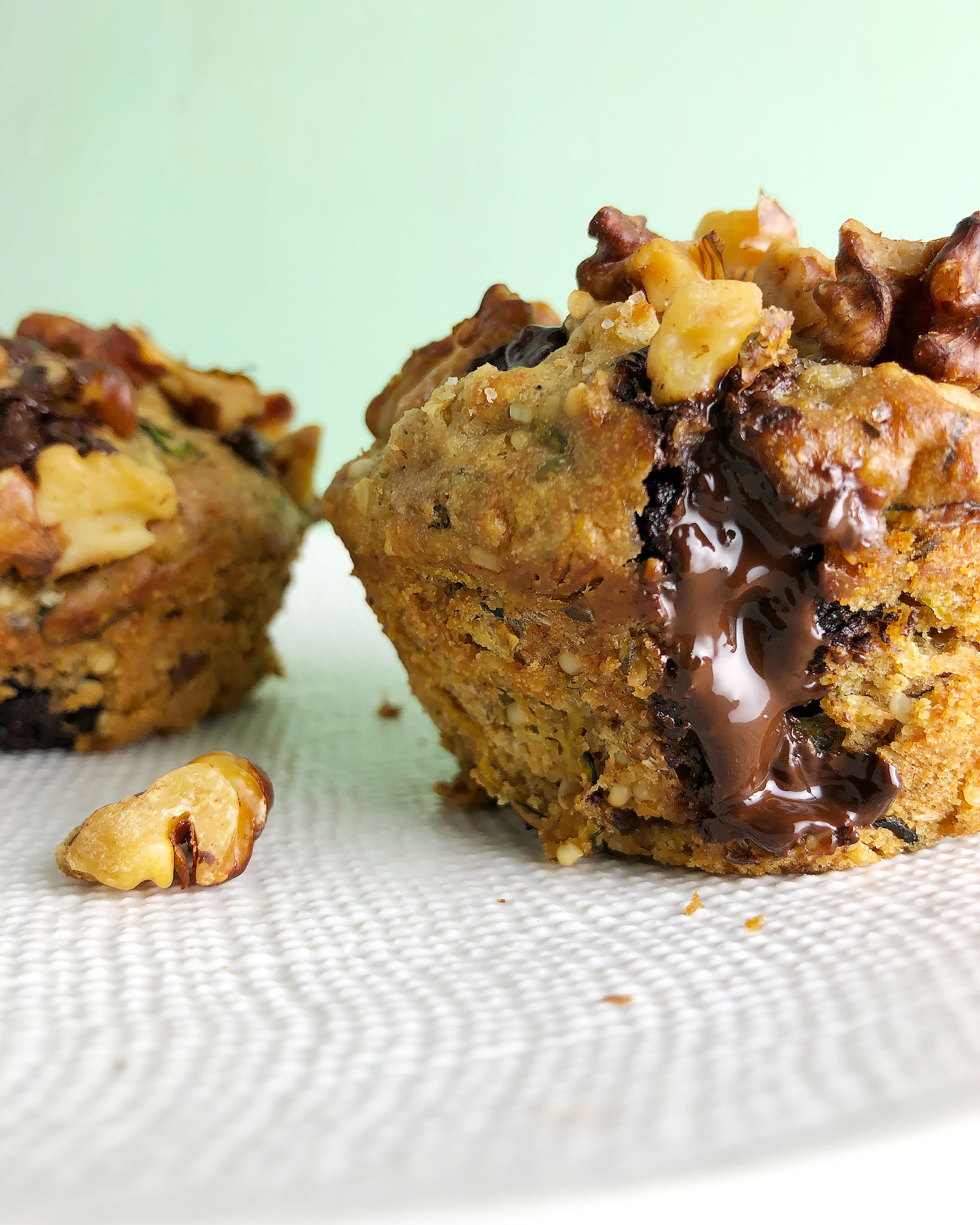Front view of Zucchini Chocolate Chunk Muffin on a white textured plate