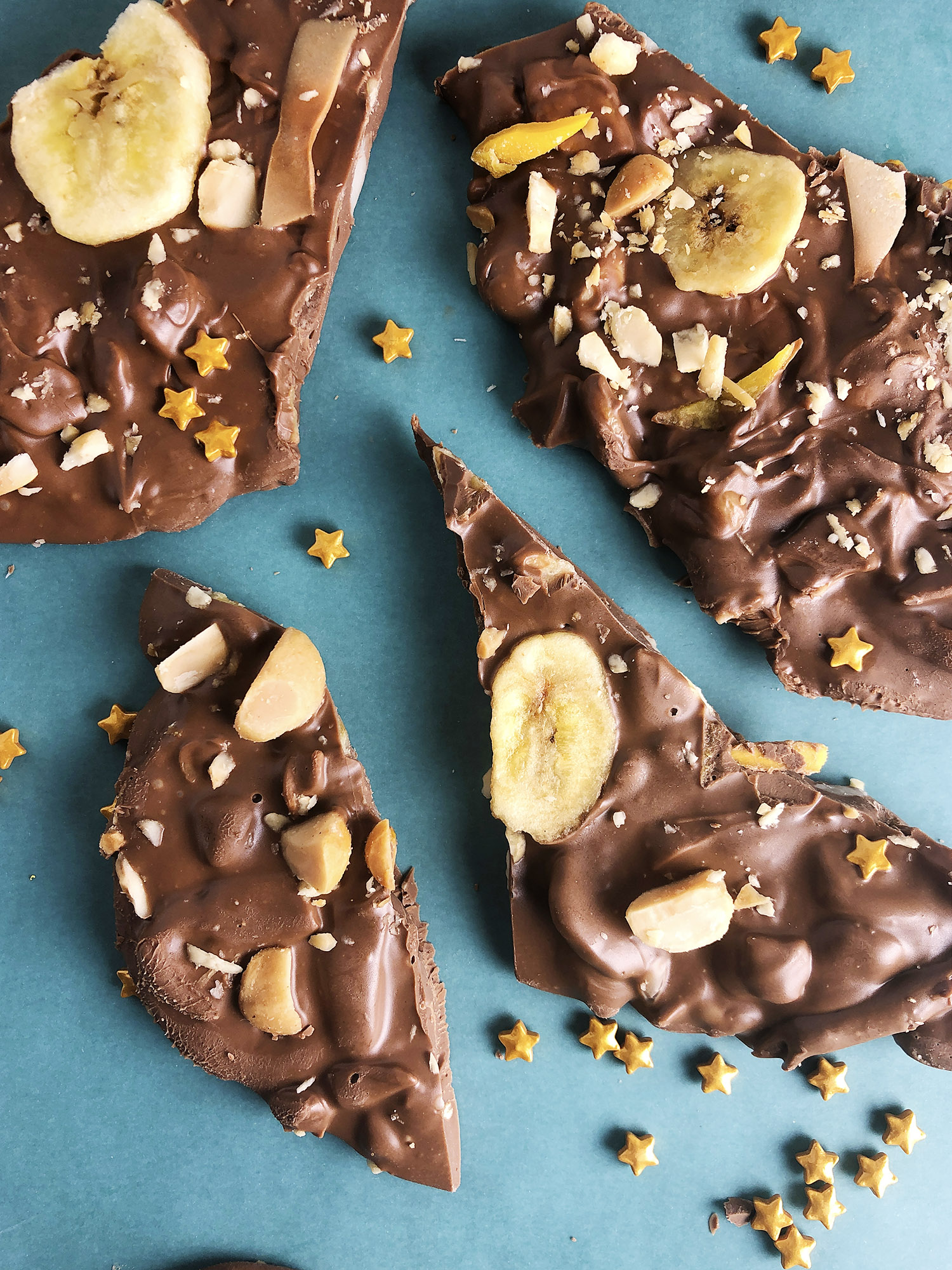 Top-down view of milk chocolate bark with dried mango, banana chips, macadamia nuts, and toasted coconut
