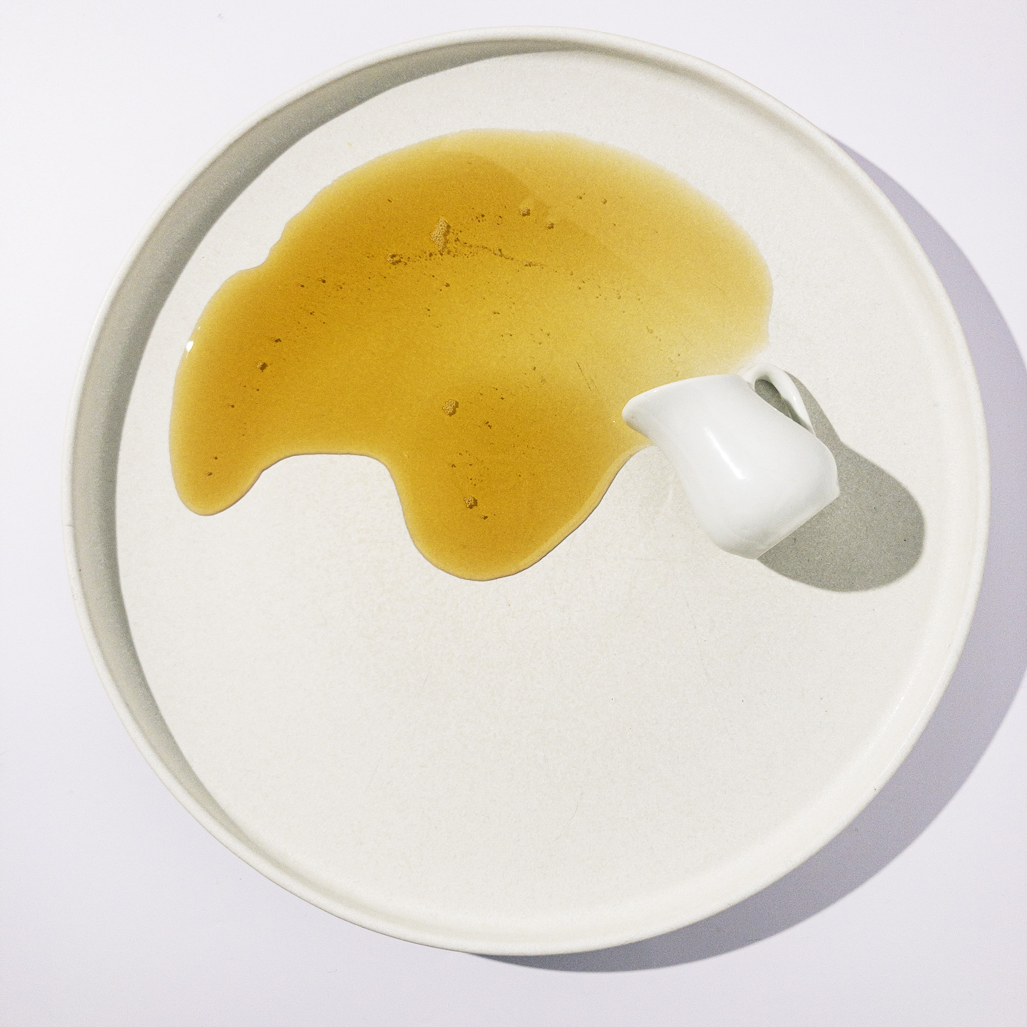maple syrup pouring from a white jug, on a white plate