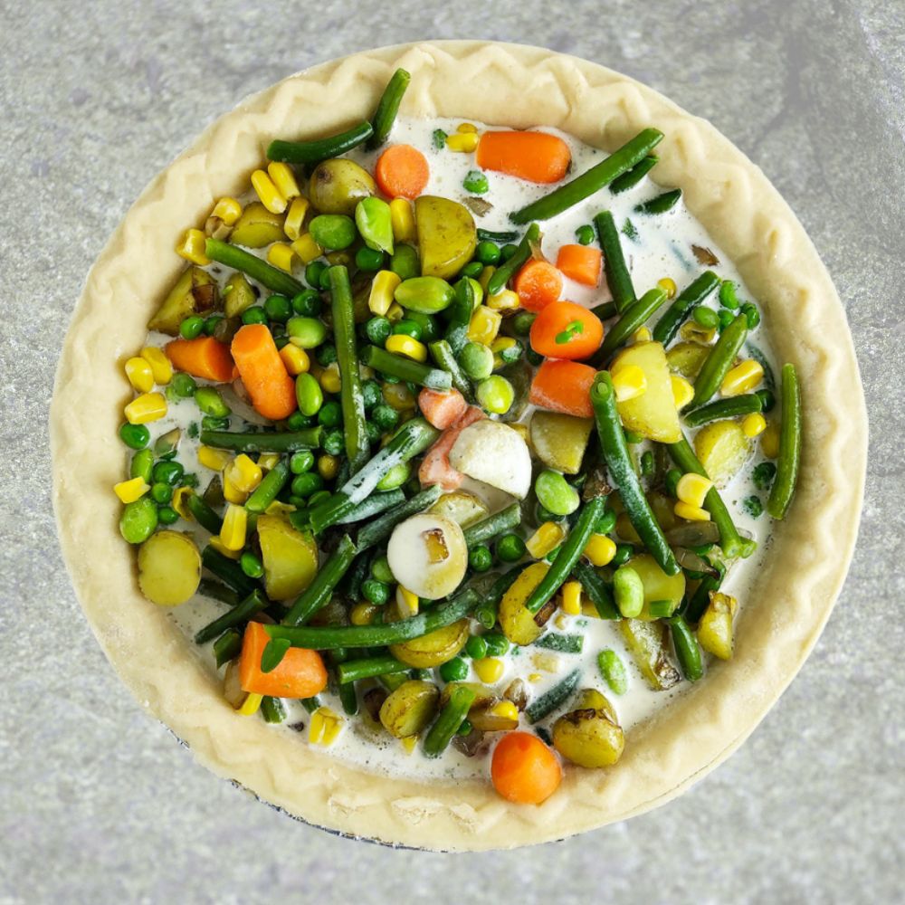 Top-down view of making vegetable pot pie, with vegetables and Mother Mix in the uncooked pie crust