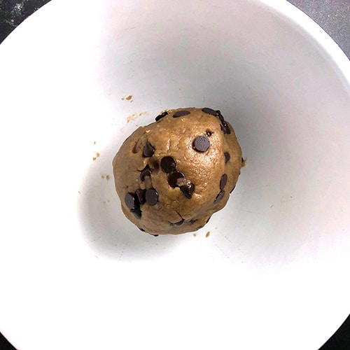 Top-down view of ball of cookie dough in white mixing bowl