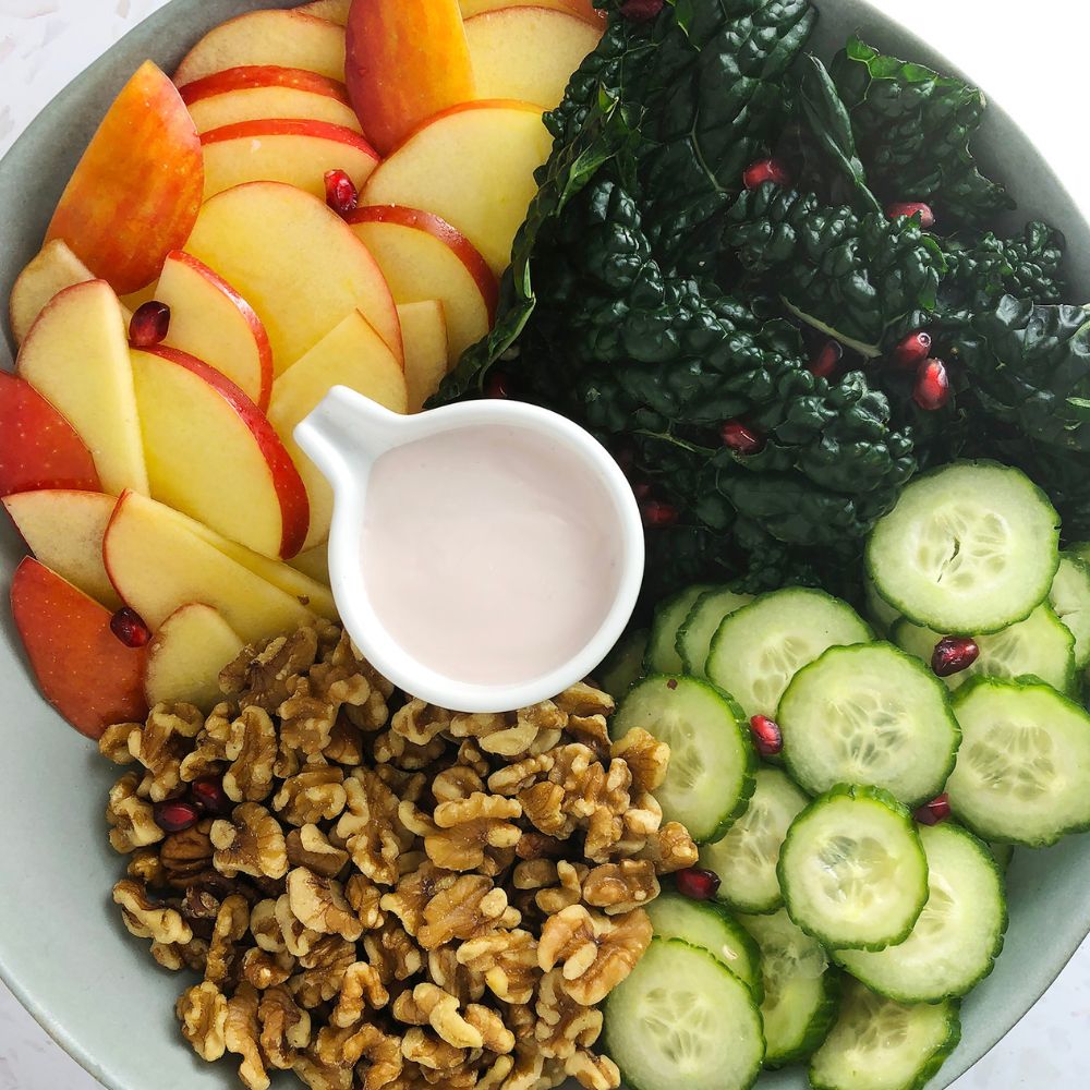 Top-down view of kale, cucumber, walnut, and apple salad