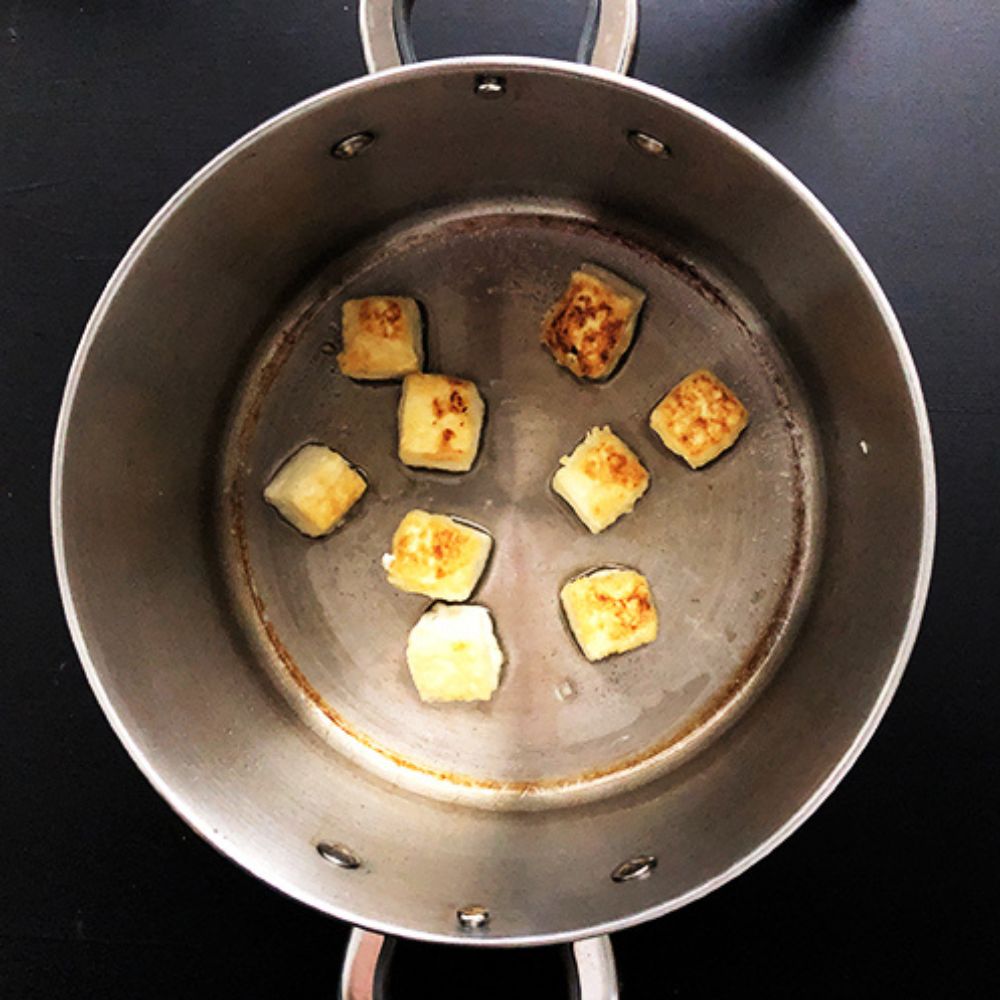 Top-down view into high-sided cooking pot, with salty crispy tofu shallow frying inside.