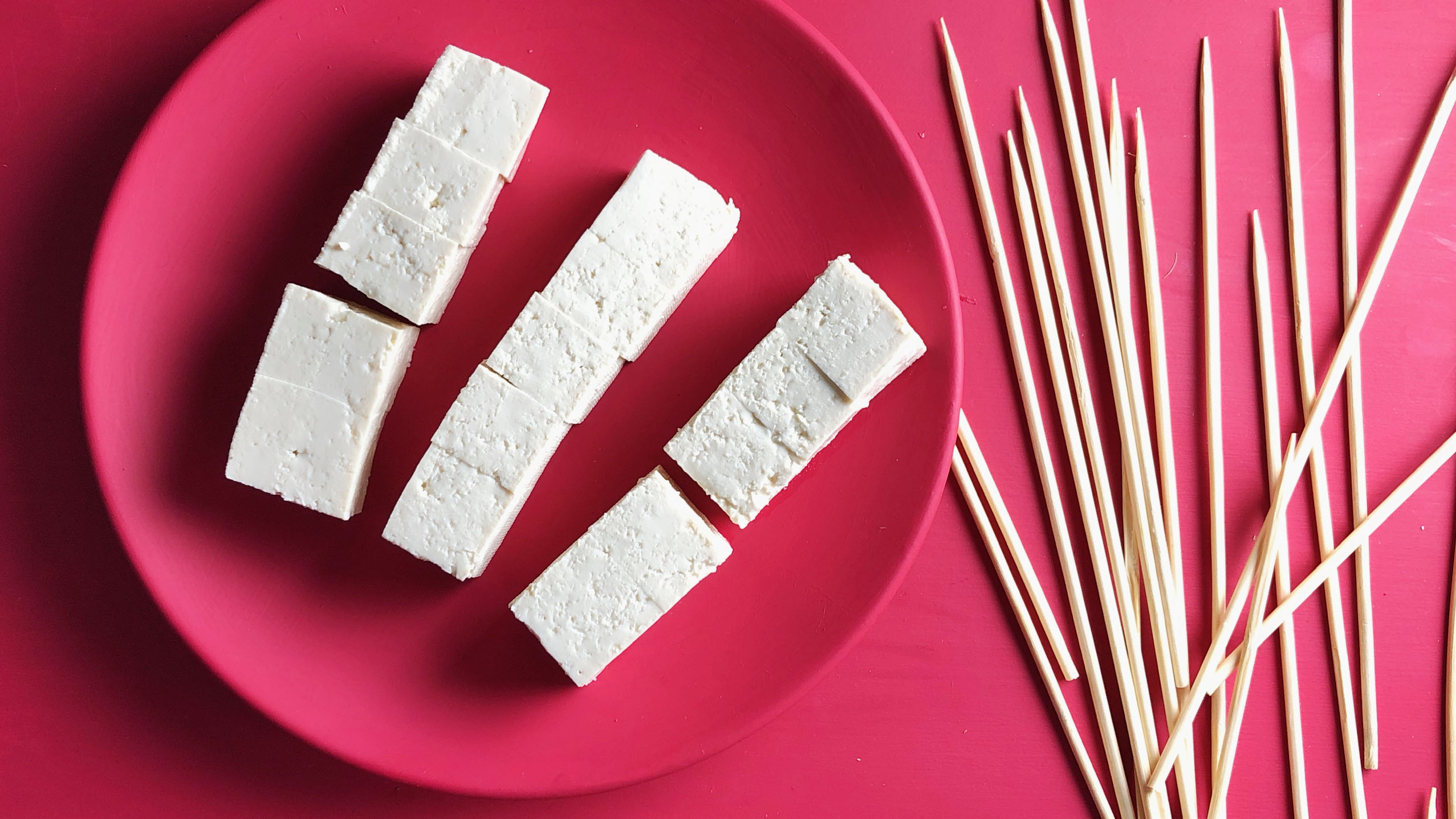 uncooked tofu cubes on a red plate