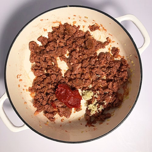 Top-down view of Beyond Beef ground meat, fried, with tomato paste and garlic. Making Beyond Beef Shepherd's Pie, step 4.