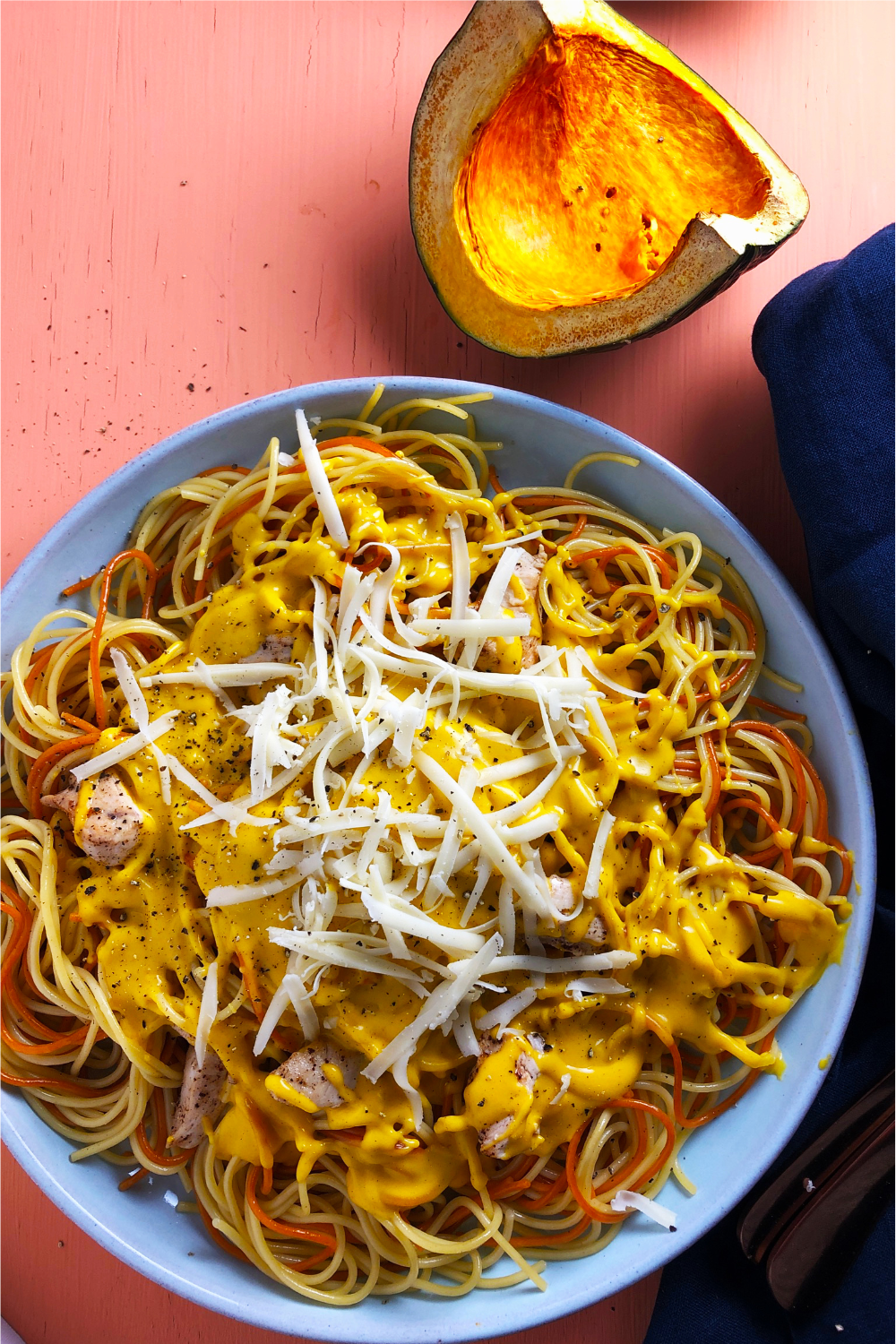 Top-down view of Kabocha Squash and Cheddar Cheese Pasta Sauce, on a blue plate against and orange background