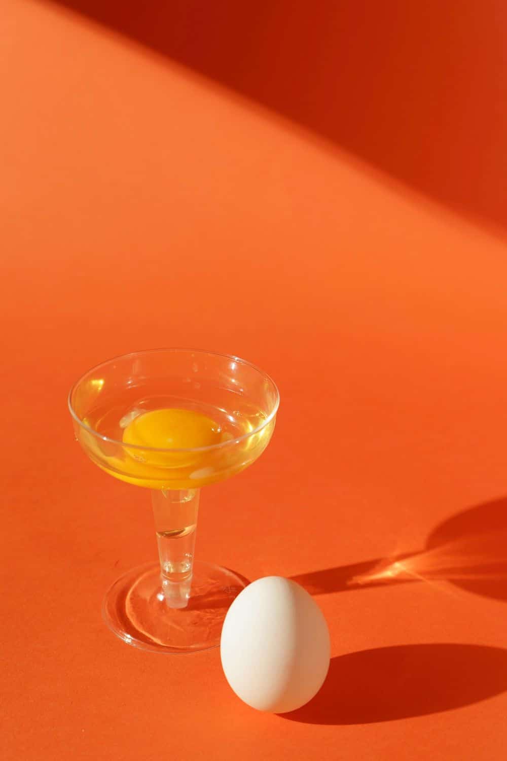 A whole egg and a cracked egg in martini glass