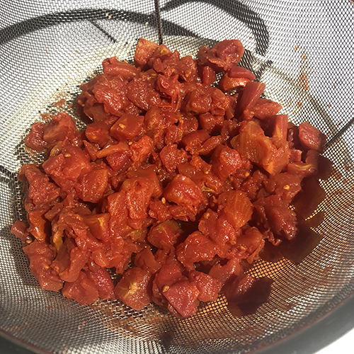 Canned diced tomatoes draining in a colander