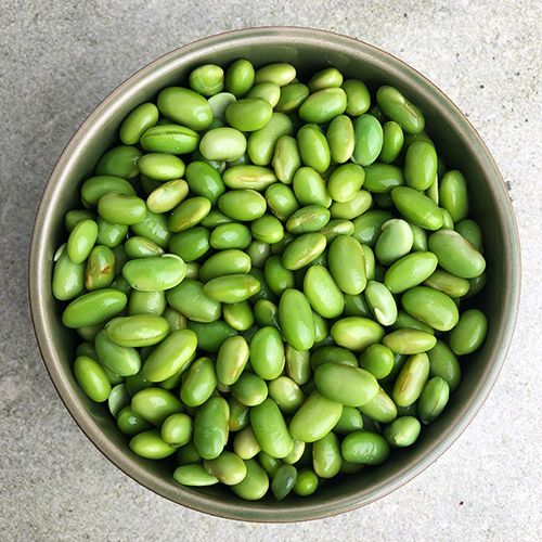 Top-down view of edamame beans in a green bowl