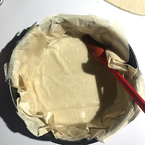Brushing coconut oil over the first layer of phyllo