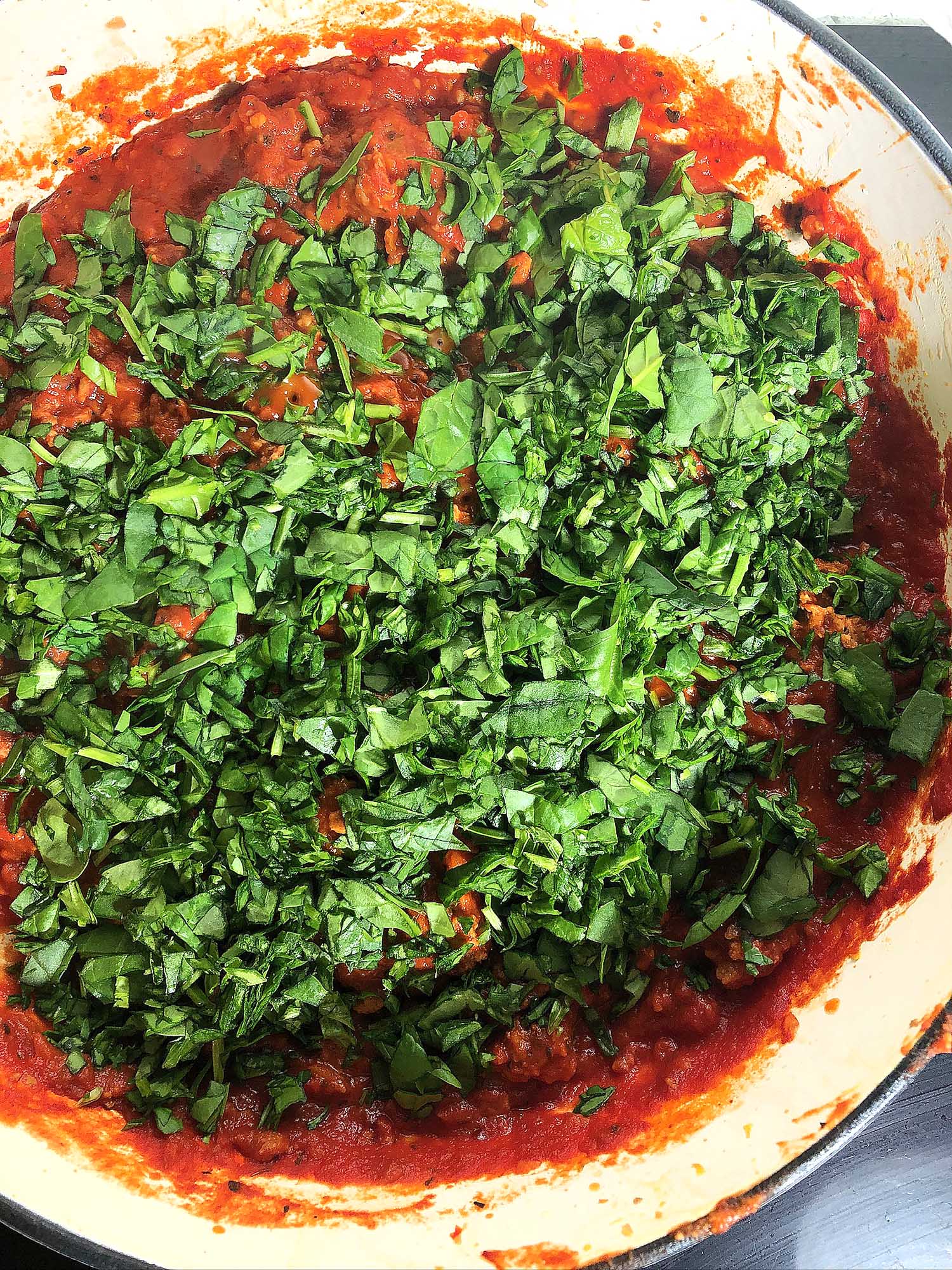 Top-down view of finely chopped spinach added to Beyond Meat Spaghetti Sauce