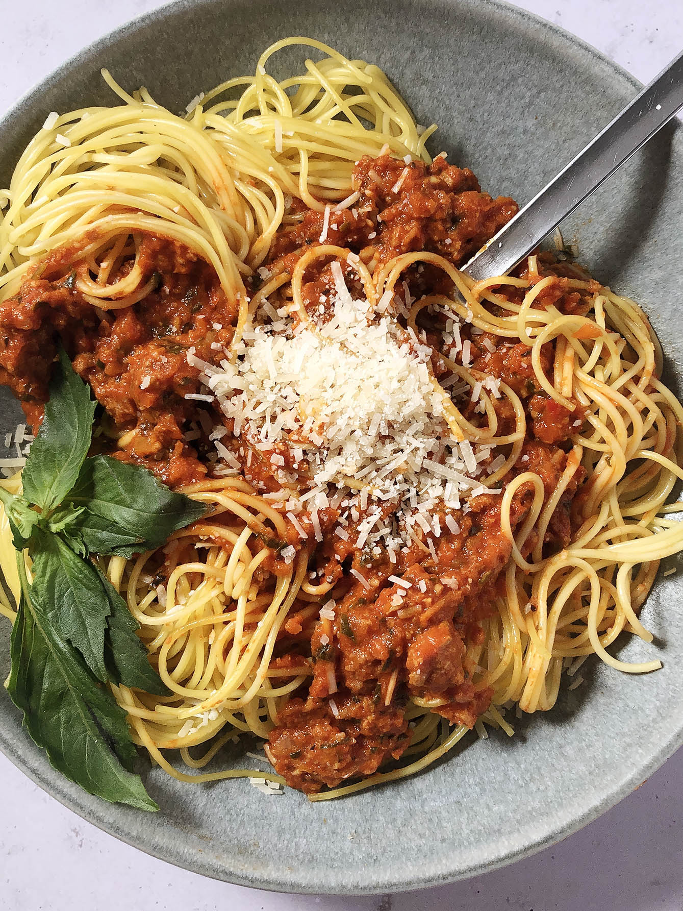 Top-down view of Beyond Meat Spaghetti Sauce, garnished with Parmesan cheese and fresh basil