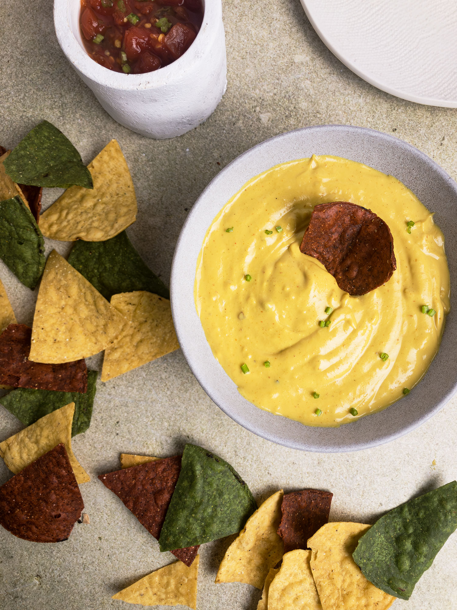 Top-down view of vegan queso surrounded by colourful corn chips.