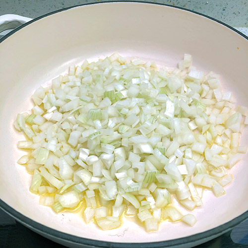 Diced onions in a white cast iron pan