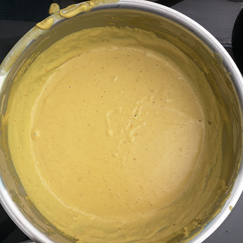 Top-down view of queso dip, cooked in saucepan.