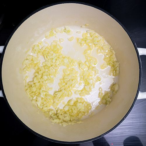 Top-down view of diced onions in white cast iron pan