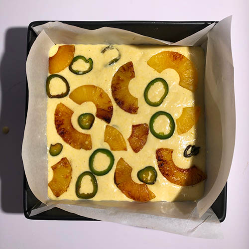 Top-down view of batter topped with caramelized pineapple and jalapeno