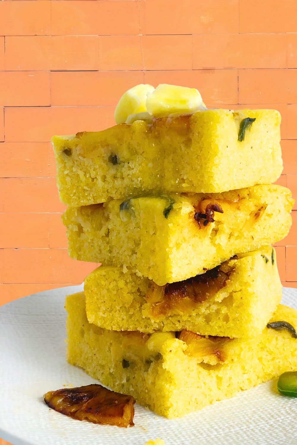 Pieces of Pineapple Jalapeno Cornbread stacked, with a pat of dairy-free butter on top. 