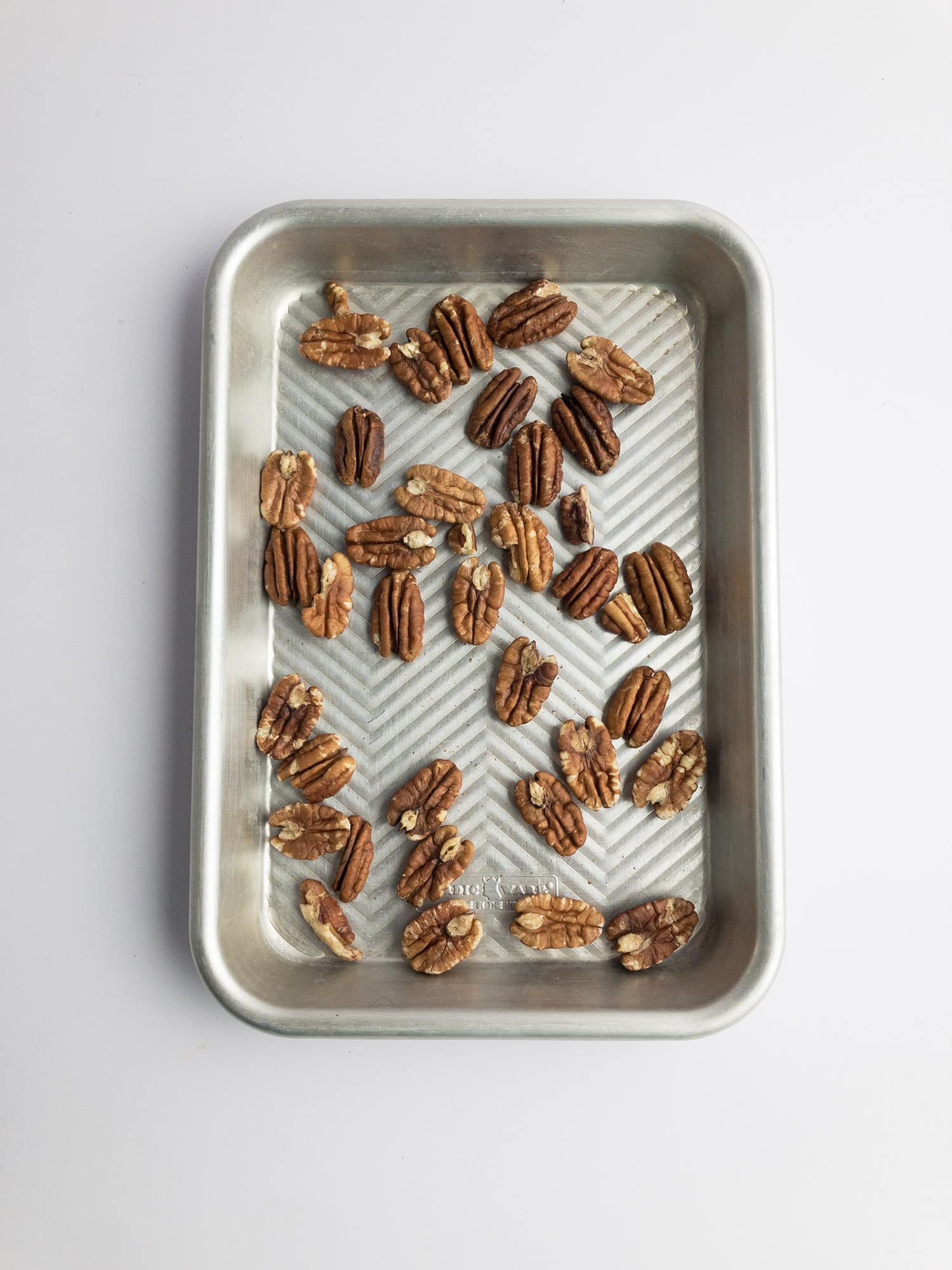 Top-down view of pecans on a baking sheet