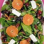 Fruit, Nut and Feta Salad, with a top-down view of the salad against a bright pink background