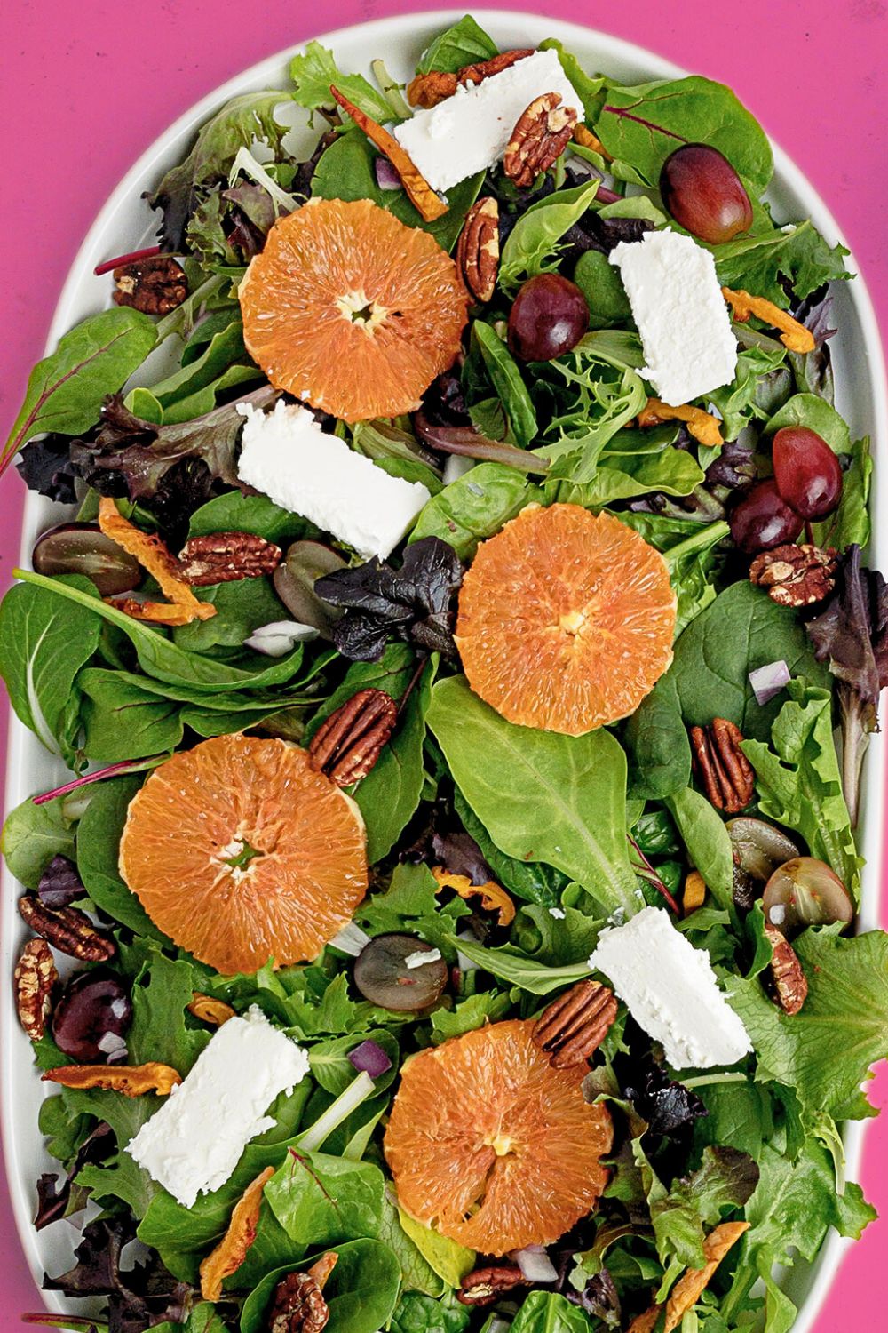 Fruit, Nut and Feta Salad, with a top-down view of the salad against a bright pink background