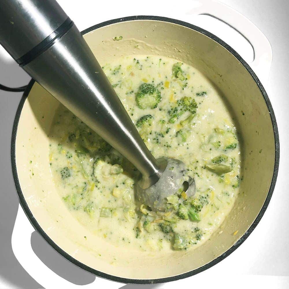 Top-down view of blending the soup with an immersion blender