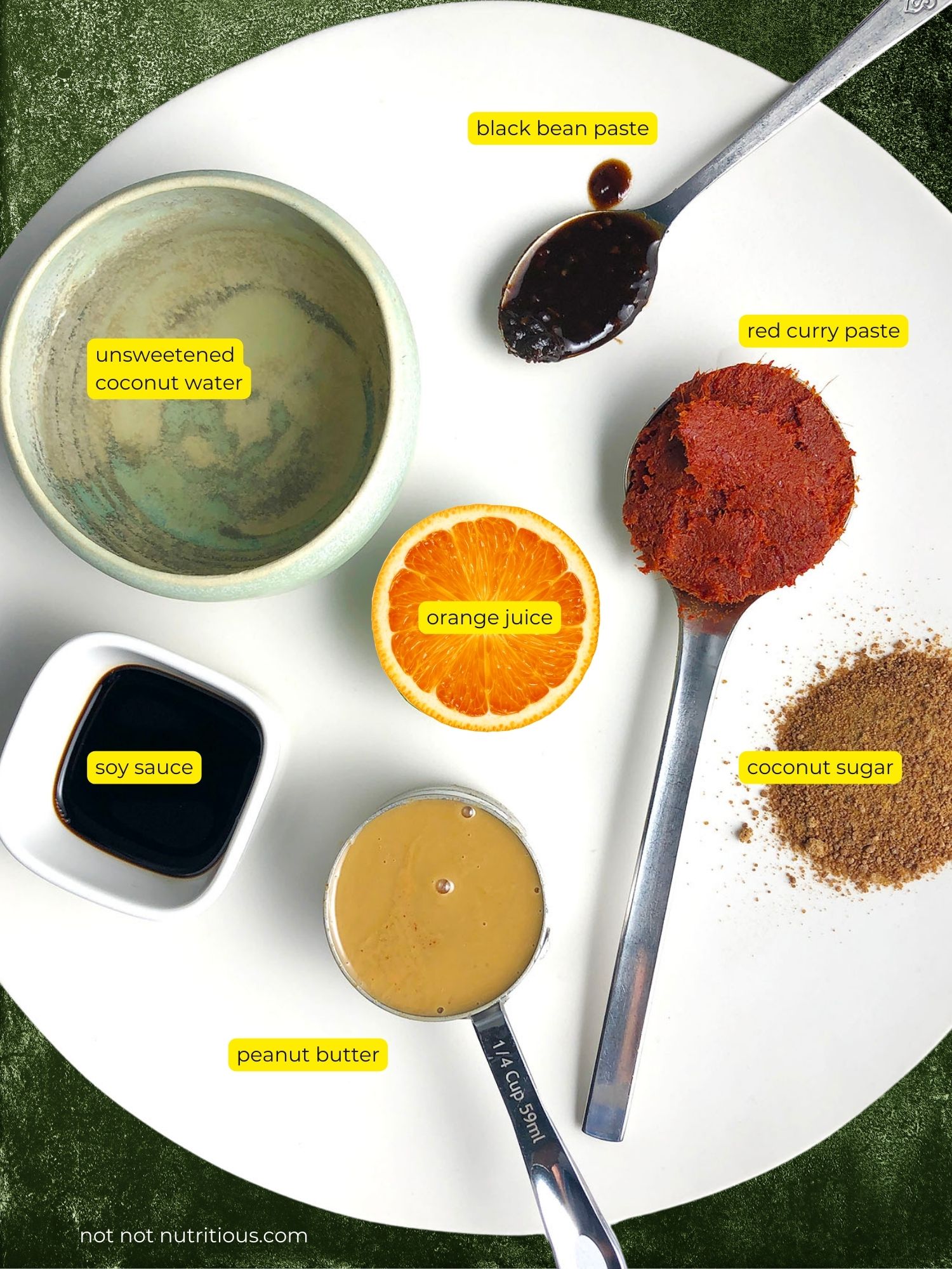 Top-down view of ingredient for Spicy Thai-inspired Peanut Sauce, including unsweetened coconut water, black bean sauce, red curry paste, coconut sugar, natural peanut butter, orange juice, and soy sauce