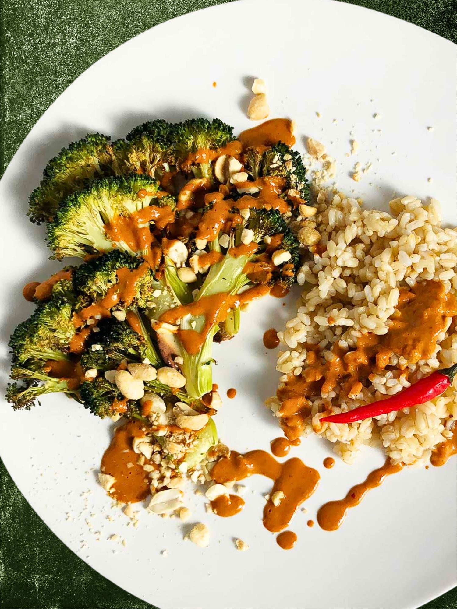 Top-down view of Spicy Thai-inspired Peanut Sauce over roasted broccoli and brown rice. Serving suggestion for the peanut sauce. 